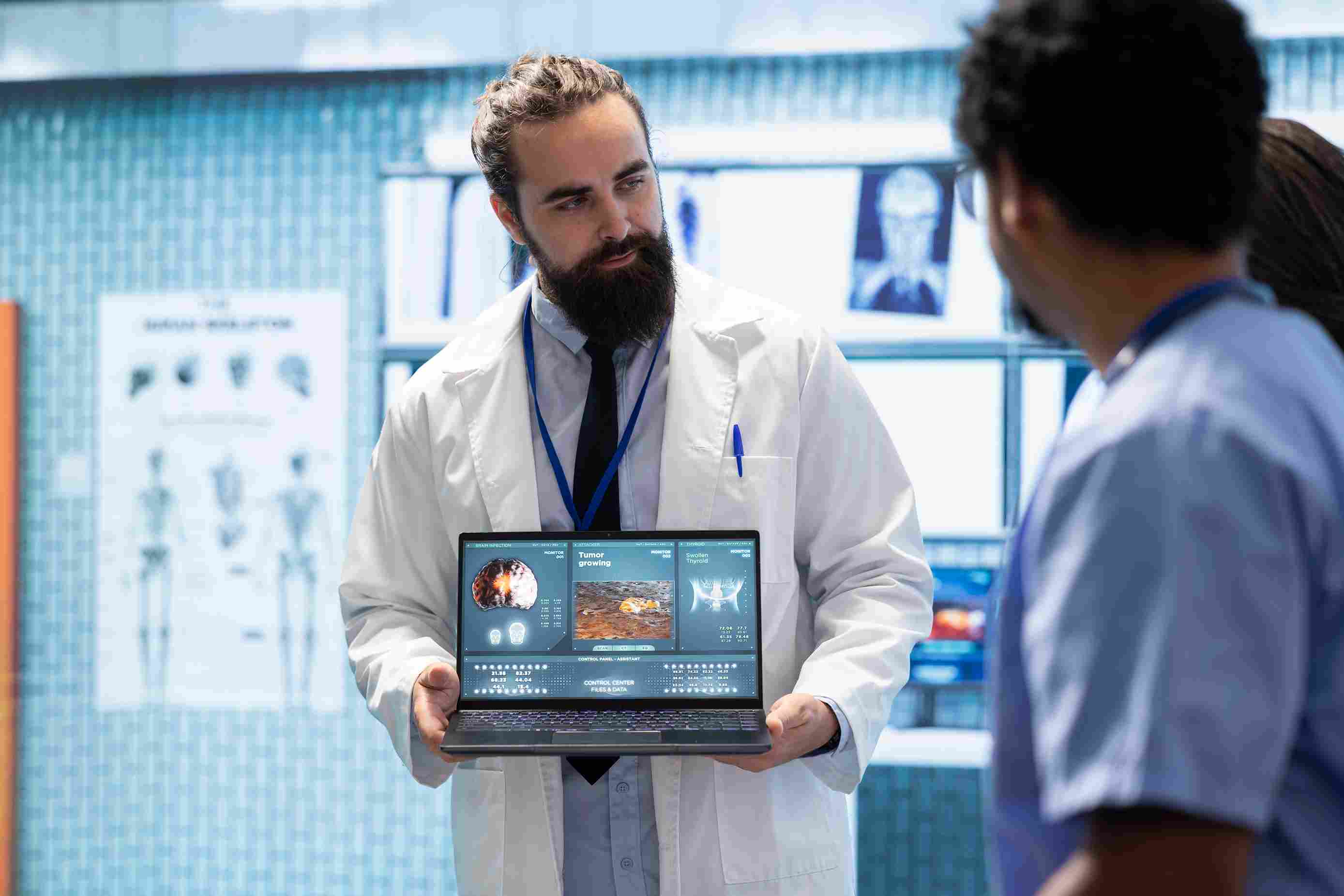 A doctor presents MRI brain scan analysis to colleagues on a laptop, facilitated by advanced hospital management software
