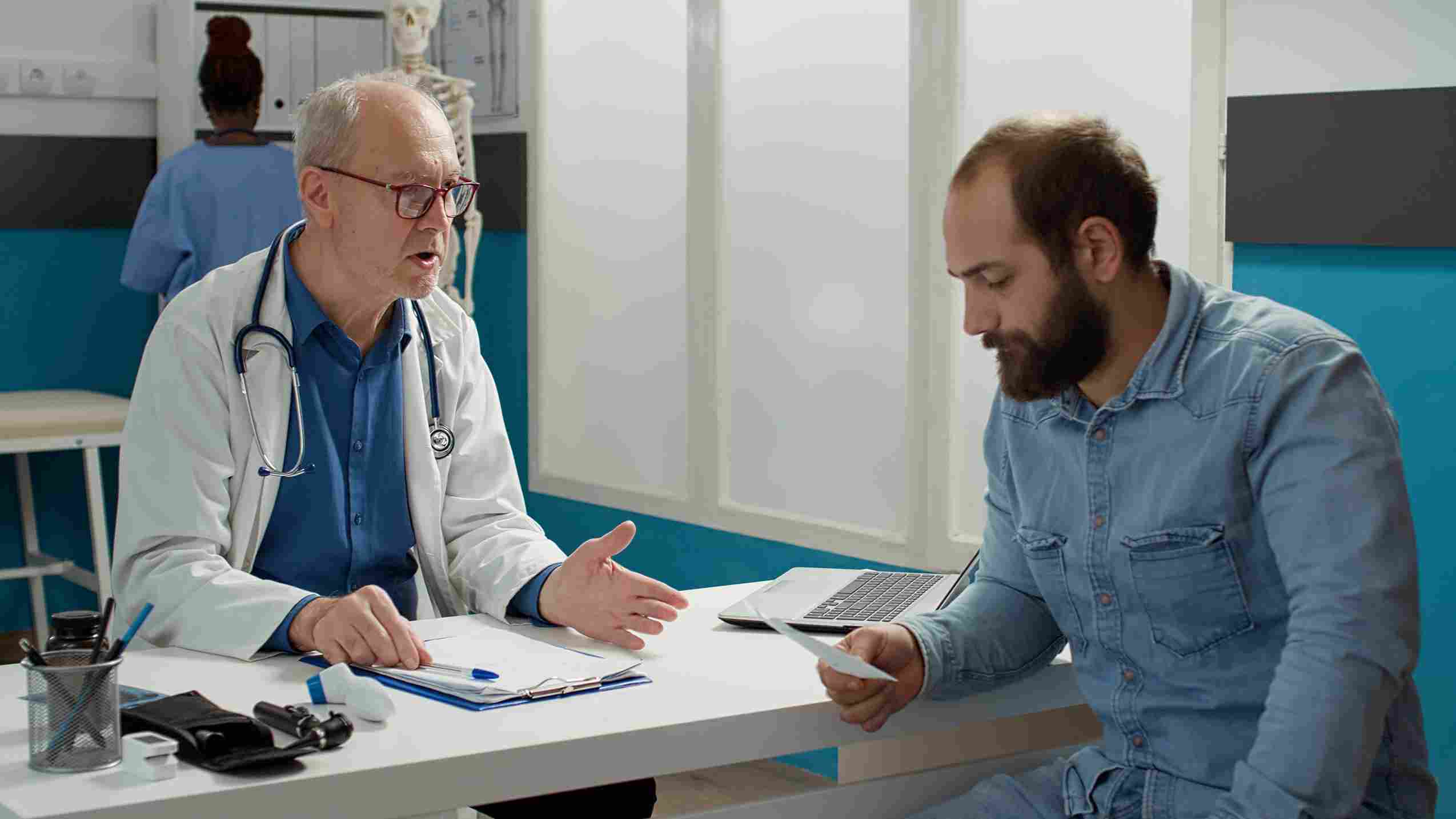 Physician handing a prescription to a patient while discussing treatment.