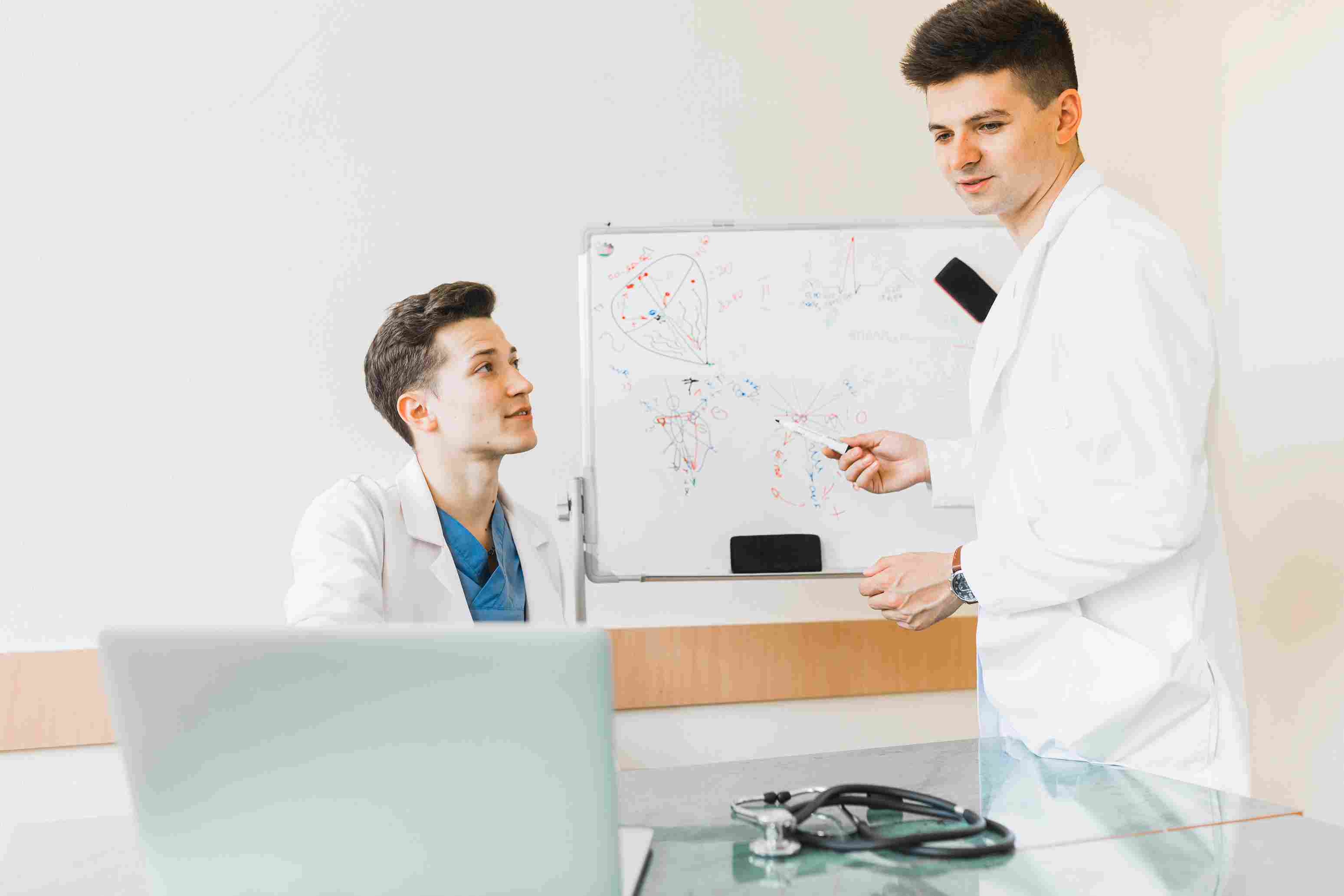 Two healthcare professionals discussing system planning in front of a whiteboard.