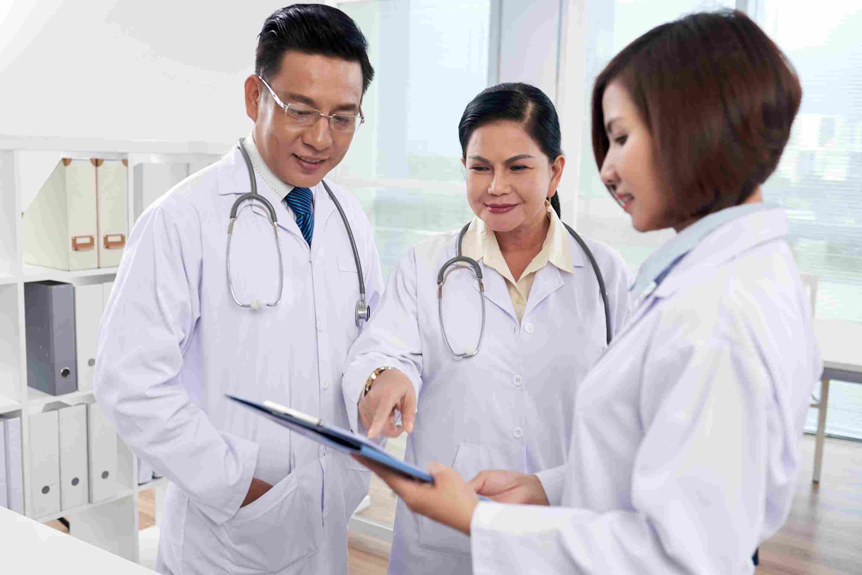 Doctors in white coats working together and analyzing medical records, illustrating teamwork and the adoption of digital healthcare management in Philippine hospitals.