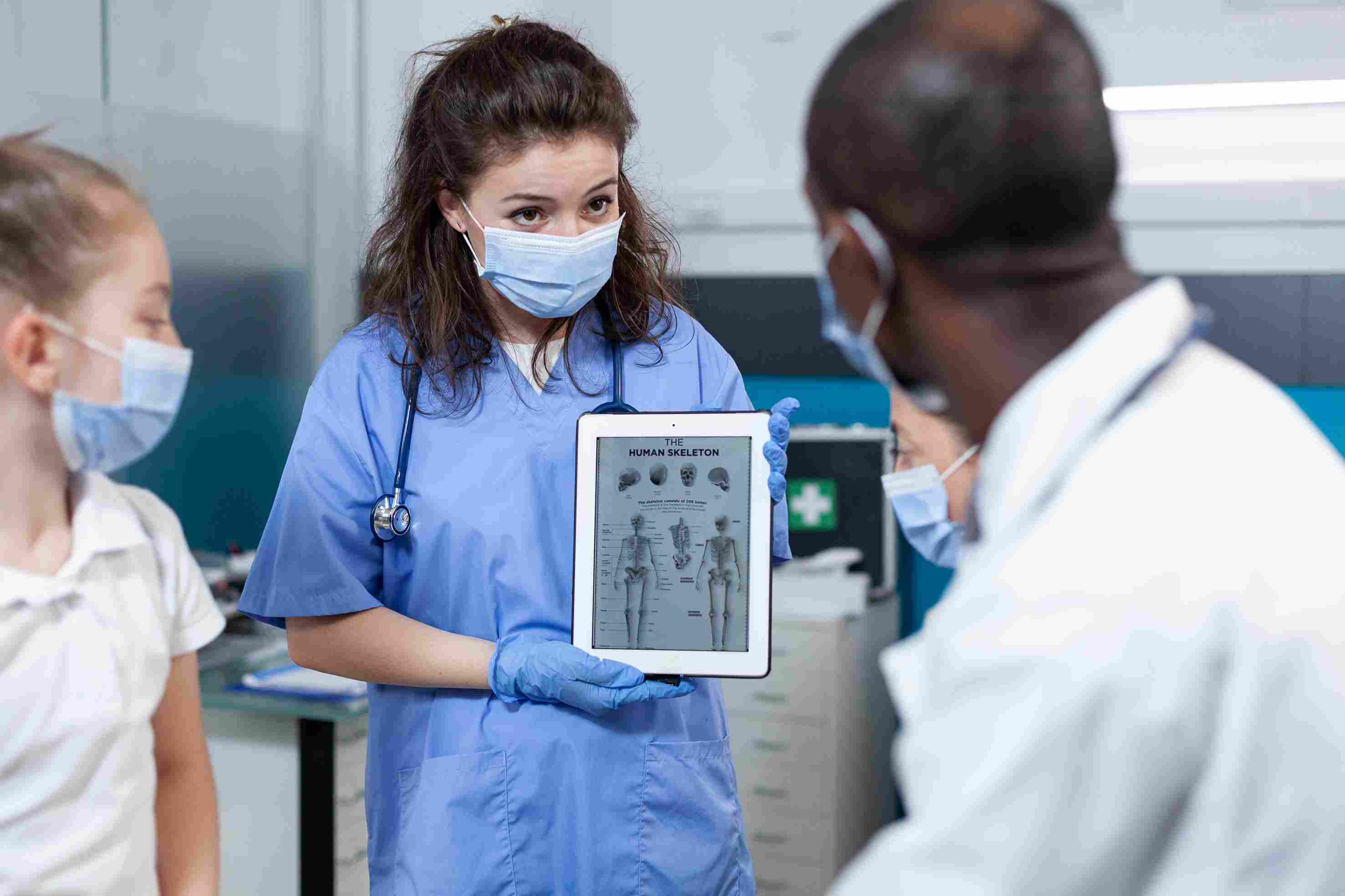 Nurse presenting digital anatomy chart via hospital management system for pediatric care and radiology review.