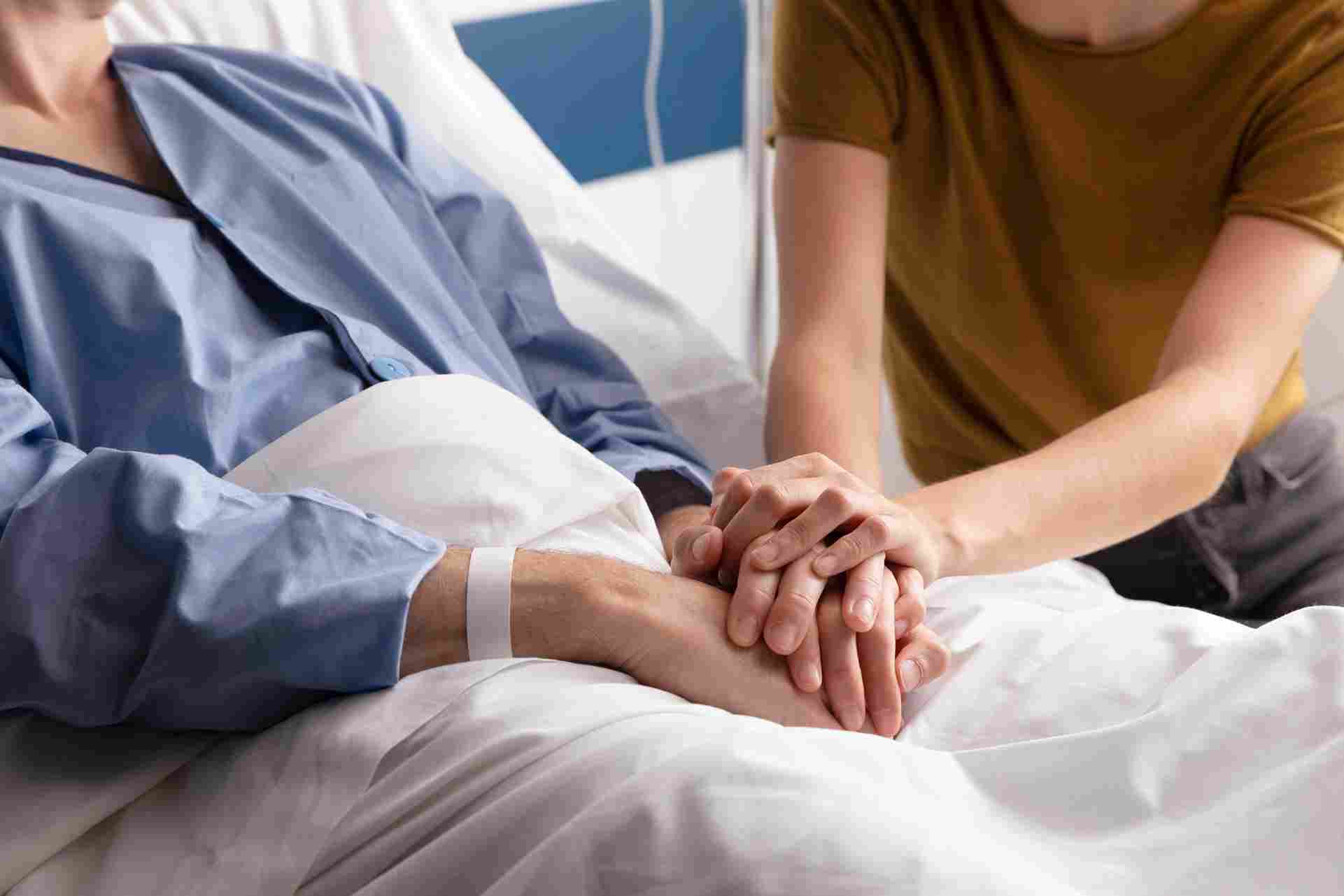 Hands holding in a hospital bed, showing patient care