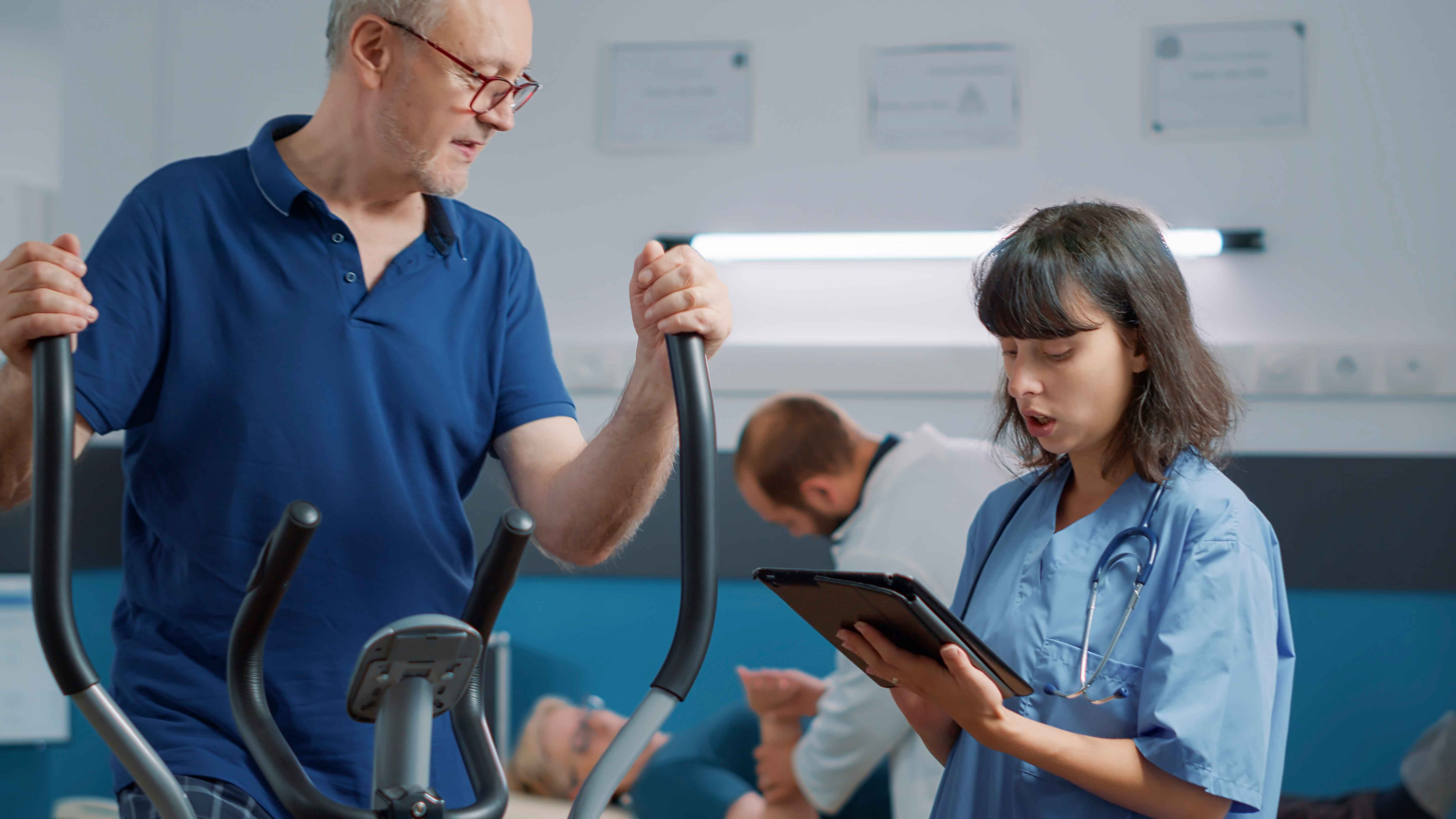 Nurse using hospital management software to monitor senior patient’s rehabilitation progress