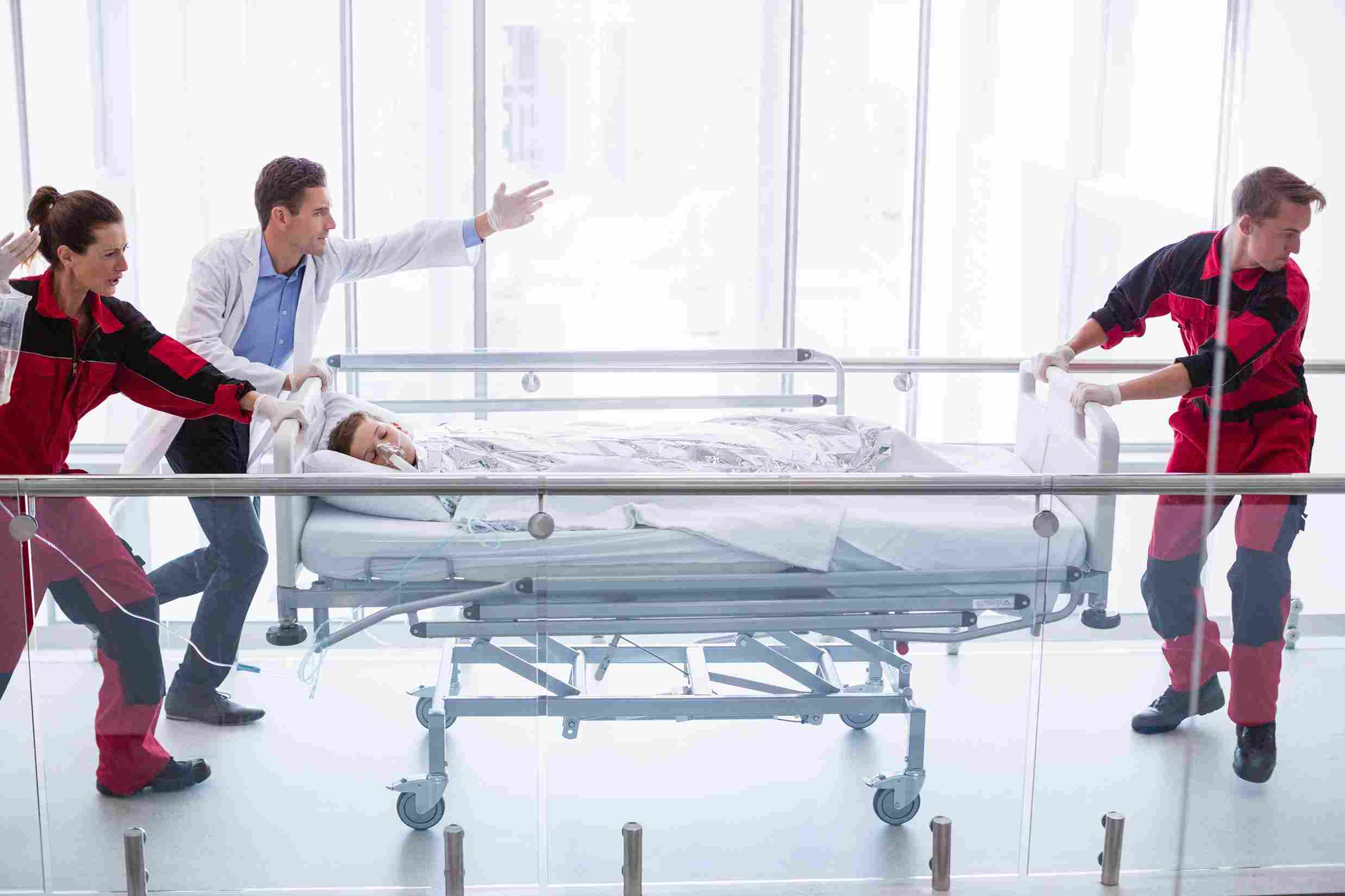 Doctors and medical staff rushing a patient on a stretcher in a hospital corridor, highlighting the urgency for digital hospital management systems