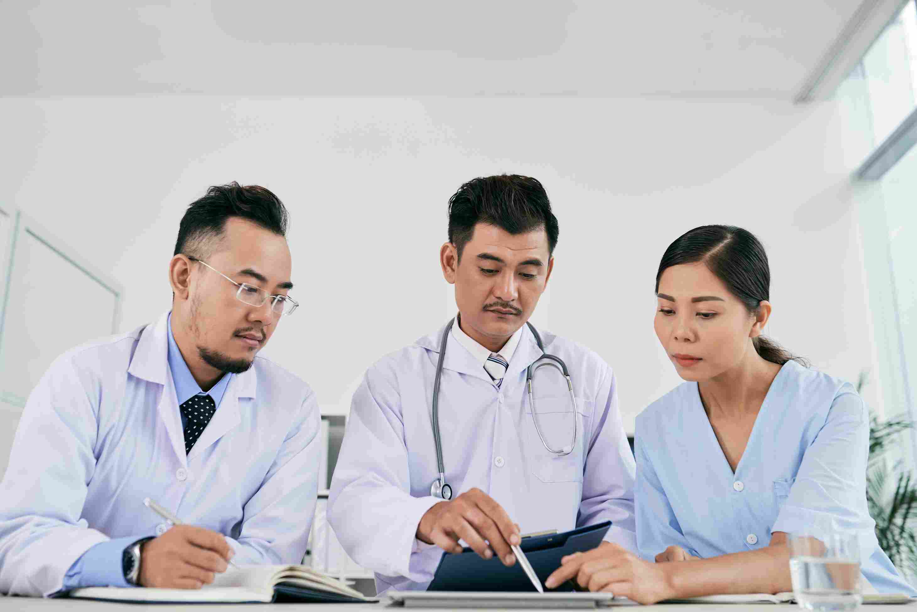 Indonesian doctors reviewing patient data on a digital tablet using hospital
