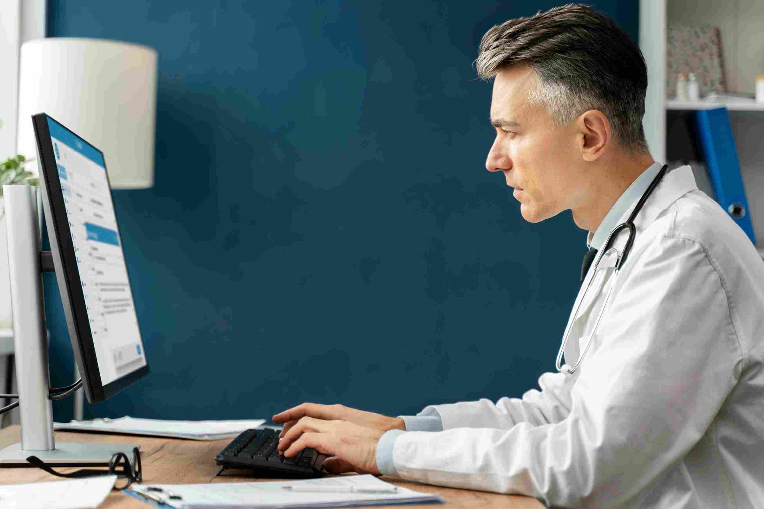 Male doctor working on a computer with hospital management software to manage patient billing and clinical data