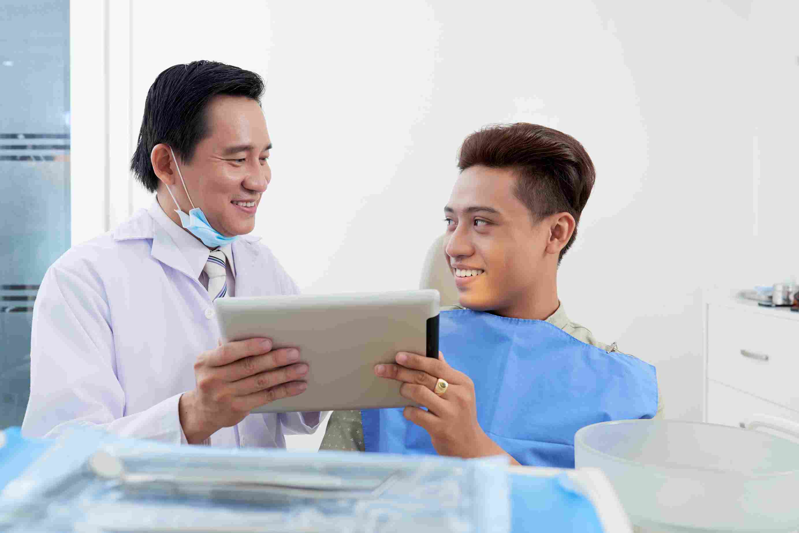 Dentist showing information on a tablet to a patient in a clinic, highlighting digital records and PhilHealth eligibility checking