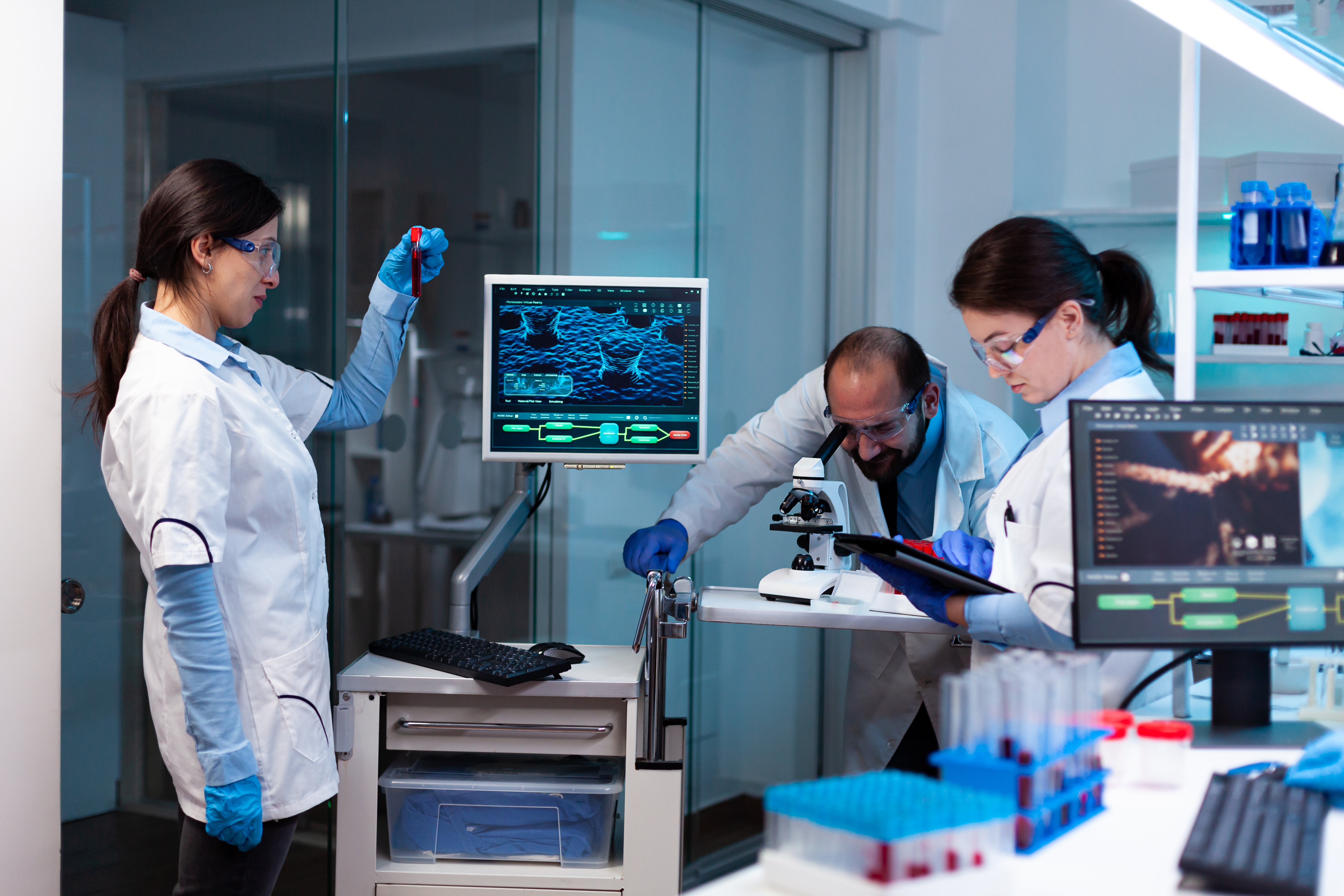Laboratory scientists analyzing blood samples using Laboratory Management Software with digital monitors showing test results and workflow data
