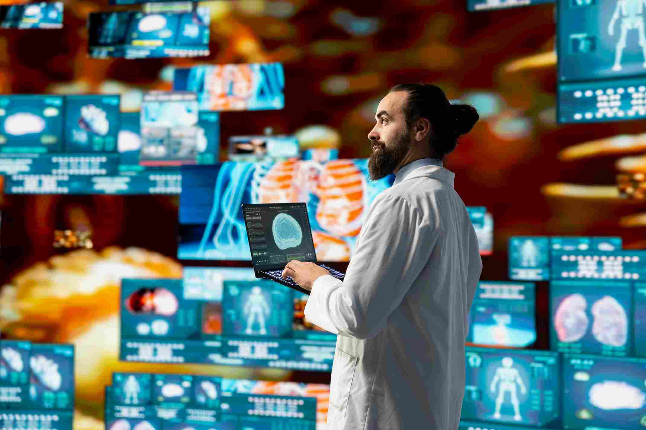 A doctor in a white coat holding a laptop displaying brain imaging data while surrounded by multiple screens showing AI-generated medical scans and clinical analytics, representing the EHR Workspace Mode of ChatGPT Epic integration where clinicians access complete patient records through an AI-connected digital platform